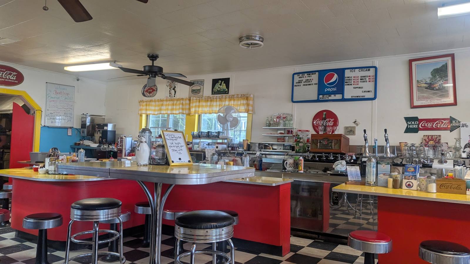 Inside Bentley's B-n-L Café: red counter with chrome stools, checkerboard floor, malt machines